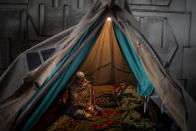 A farmer lights a bidi, or hand-rolled tobacco, as he sits inside a tent with a fellow farmer, blocking a major highway in protest against new farm laws at the Delhi-Uttar Pradesh state border, India, Friday, Jan. 8, 2021. (AP Photo/Altaf Qadri)