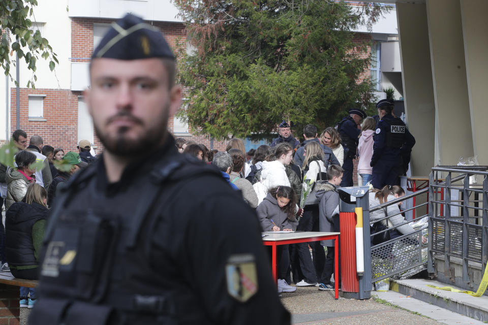 A police officer looks on as children enter the Gambetta high school after a bomb alert Monday, Oct. 16, 2023 in Arras, northern France. French authorities say the high school where a teacher was fatally stabbed in an attack last week has been evacuated over a bomb alert, as France's President cut short travel plans abroad to host a security meeting Monday.(AP Photo/Michel Spingler)