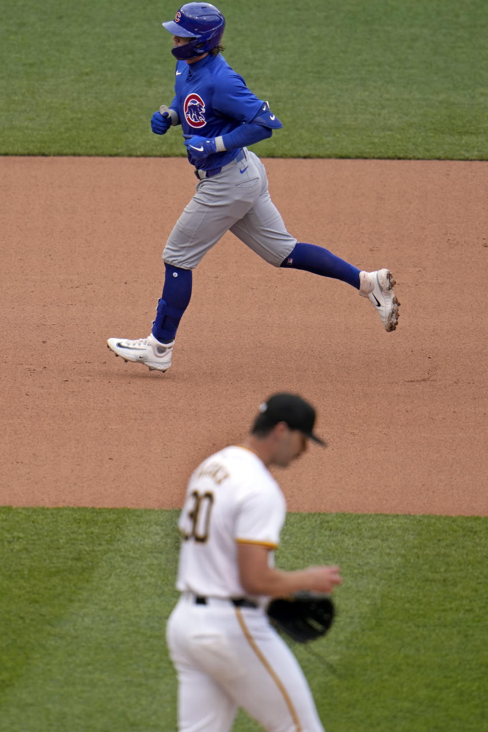 Chicago Cubs' Nico Hoerner, top, rounds the bases after hitting a solo home run off Pittsburgh Pirates starting pitcher Paul Skenes (30) during the fourth inning of a baseball game in Pittsburgh, Saturday, May 11, 2024. (AP Photo/Gene J. Puskar)