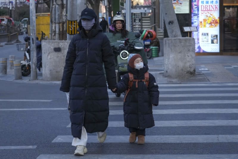 <cite>牽著孩子過馬路的中國女性。（AP）</cite>