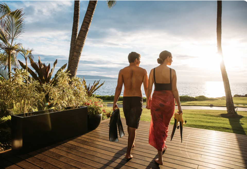 A couple walking out over their sun drenched deck at the Wailea beach resort