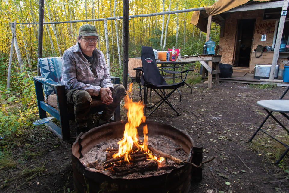 Jean L'Hommecourt warms at the fire outside the cabin she has built near the Fort McKay First Nation's village, about an hour's drive north of Fort McMurray in Alberta. (Michael Kodas)