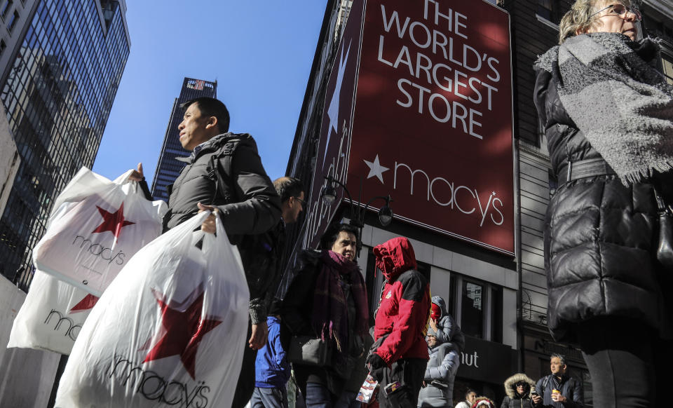 A shopper leaves Macy's department store with bags in both hands during Black Friday shopping, Friday Nov. 29, 2019, in New York. Black Friday shoppers fought for parking spots and traveled cross-state to their favorite malls, kicking off a shortened shopping season that intensified the mad scramble between Thanksgiving and Christmas. (AP Photo/Bebeto Matthews)