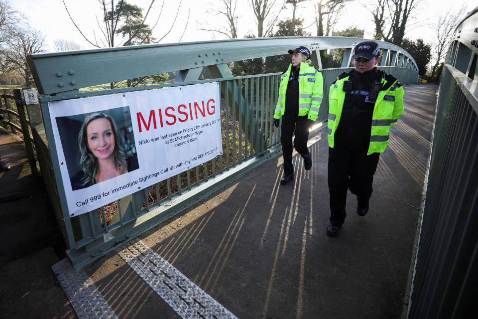 Polizisten gehen über eine Brücke, an der ein Suchplakat für die vermisste Nicola Bulley aufgehängt ist. (Bild: REUTERS/Phil Noble)