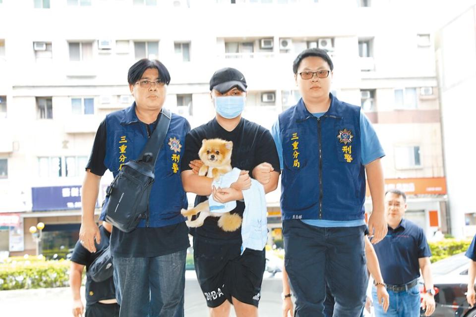 涉嫌新北市三重區祖孫三代3屍命案的張姓男子（中），12日遭警方逮捕，帶回三重警分局時，他懷中仍緊抱愛犬。（張鎧乙攝）