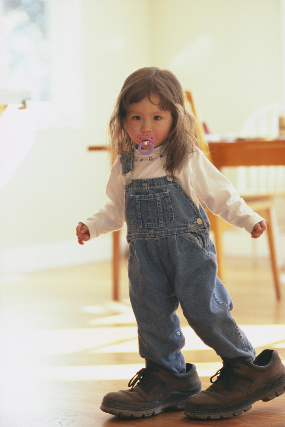 Toddler girl walking around in her dad's shoes