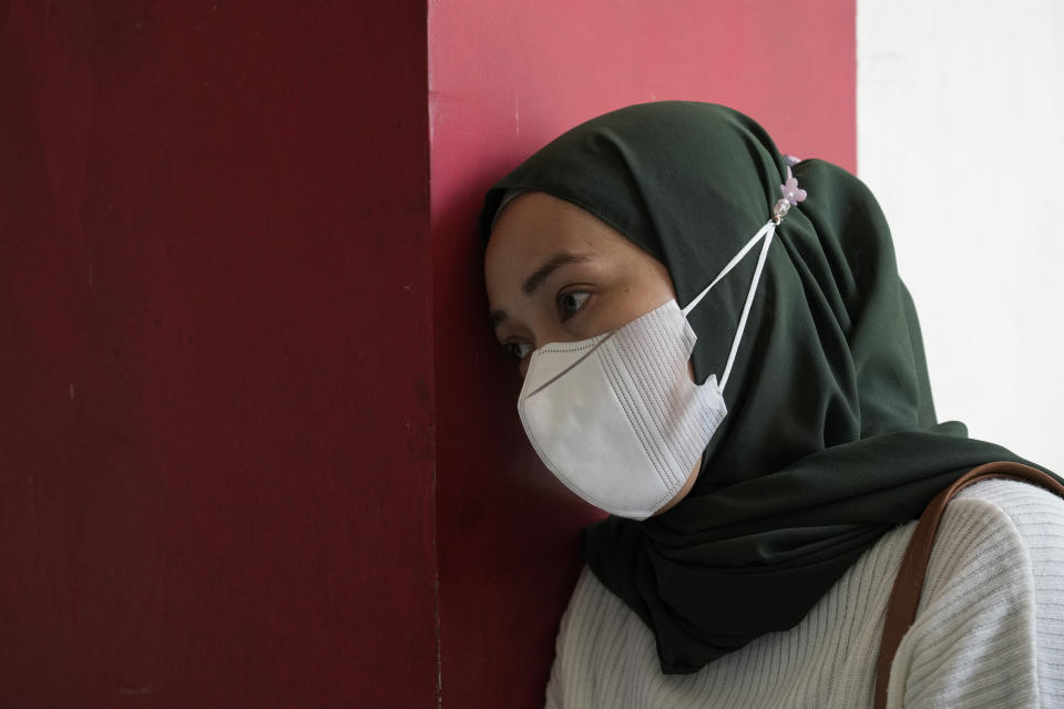 A woman takes a moment for the victims of Saturday's soccer match stampede in front of gate 13 of the Kanjuruhan Stadium in Malang, Indonesia, Tuesday, Oct. 4, 2022. Indonesian police said Tuesday that the gates at the soccer stadium where police fired tear gas and set off a deadly crush were too small and could only accommodate two at a time when hundreds were trying to escape. (AP Photo/Achmad Ibrahim)