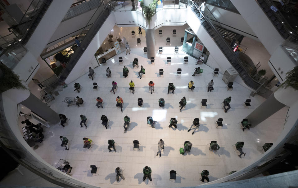 People practice social distancing as they sit on chairs spread apart in a waiting area for take-away food orders at a shopping mall in hopes of preventing the spread of the coronavirus in Bangkok, Thailand, Tuesday, March 24, 2020. (AP Photo/Sakchai Lalit)