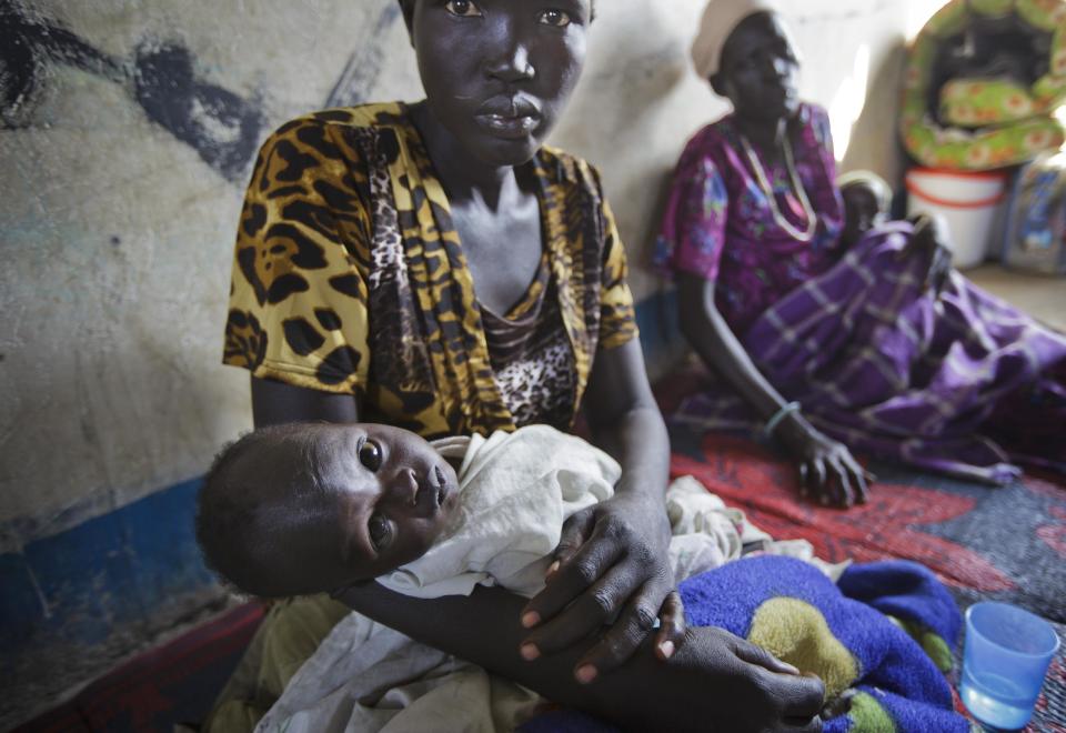 In this photo taken Thursday, Jan. 2, 2014, 7-month-old boy Dhieu Ding Chol, left, and 5-month-old boy Thuch Jong Kuch, right, are held by their mothers as they receive treatment for dehydration, vomiting and diarrhea, likely caused by the lack of any sanitation where they are now living, at a clinic run by Medecins Sans Frontieres (Doctors Without Borders) set up in a school building in the town of Awerial, South Sudan. (AP Photo/Ben Curtis)