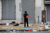 A man stands holds merchandise outside of a damaged store after protest, Tuesday, Oct. 27, 2020, in Philadelphia over the death of Walter Wallace, a Black man who was killed by police in Philadelphia. Police shot and killed the 27-year-old on a Philadelphia street after yelling at him to drop his knife, sparking violent protests that police said injured 30 officers and led to dozens of arrests. (AP Photo/Michael Perez)