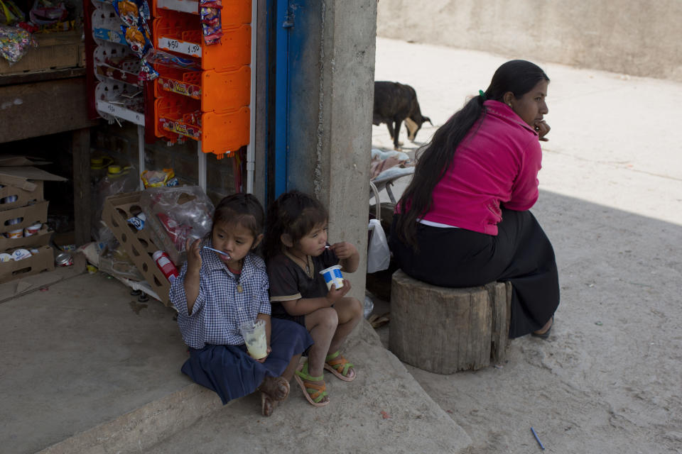 In this Feb. 11, 2014 photo, children snack on custard and yogurt as they sit on the stoop of a small convenience store in Cochoapa El Grande, Mexico. More than a year after President Enrique Pena Nieto launched what he called a national crusade against hunger, the government says 3 million Mexicans are eating better. However, independent experts say that number is questionable and the crusade against hunger appears to be doing far less than advertised. (AP Photo/Dario Lopez-Mills)