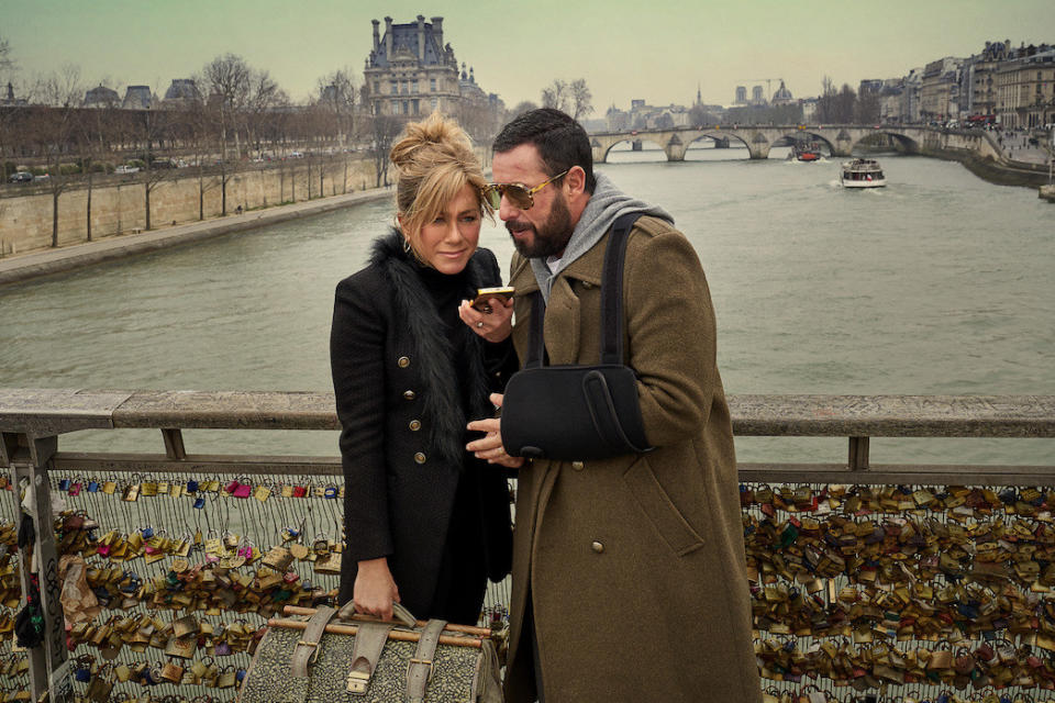 a couple holding luggage and using their phone on the street