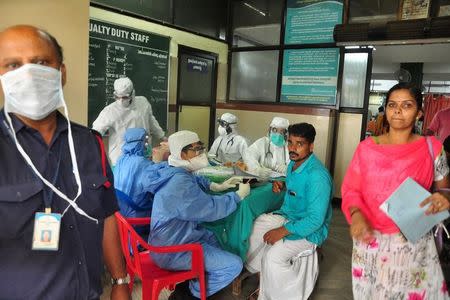 Medics wearing protective gear examine a patient at a hospital in Kozhikode in Kerala May 21, 2018. REUTERS/Stringer