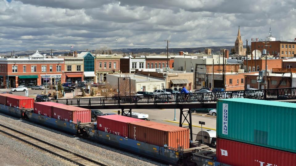 "Laramie, Wyoming, USA - March 30, 2013: A cyclist on an overpass over a rail yard in Laramie with other people in the background.