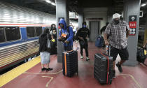 Travelers arriving on a train that originated in Miami carry their luggage at Amtrak's Penn Station, Thursday, Aug. 6, 2020, in New York. Mayor Bill de Blasio is asking travelers from 34 states, including Florida where COVID-19 infection rates are high, to quarantine for 14 days after arriving in the city. (AP Photo/Mark Lennihan)