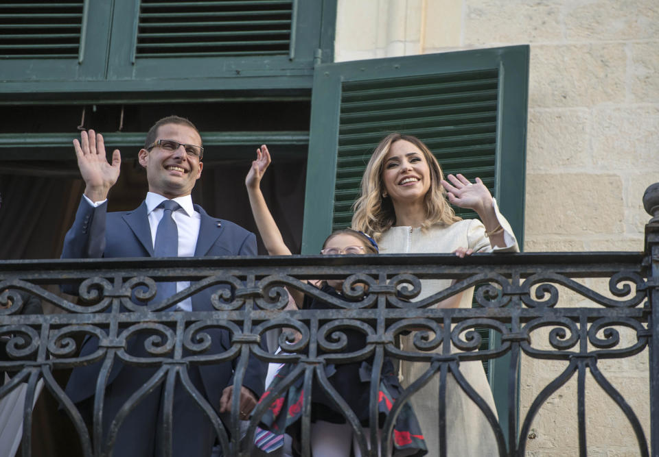 The new Prime Minister of Malta Robert Abela waves to the crowd from the President of Malta's balcony after the swearing in ceremony, together with his wife Lydia Abela and his daughter Giorgia Mae, Monday, Jan. 13, 2020. Abela is replacing Joseph Muscat after weeks of protests demanding accountability in the investigation of the car bomb slaying of an anti-corruption journalist who targeted his government. (AP Photo/Rene' Rossignaud)