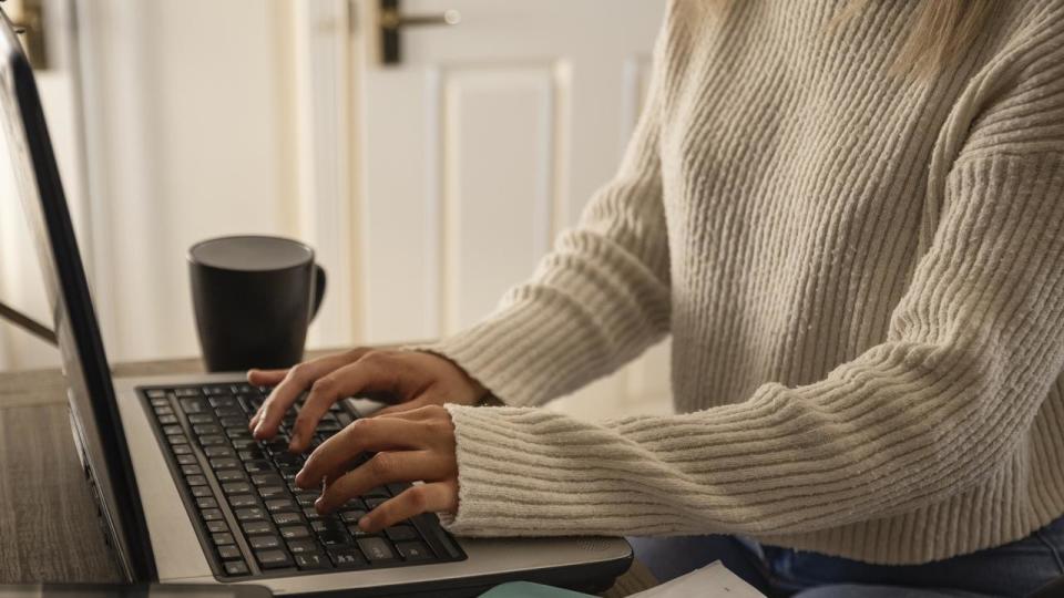 An unrecognisable young woman using her laptop and completing some work at home in Northumberland, North East England.