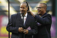Former Cleveland baseball player Manny Ramirez, left, is helped into his Hall of Fame jacket by former teammate Carlos Baerga, right, during induction ceremonies into the Cleveland Guardians Hall of Fame before a game between the Detroit Tigers and the Guardians, Saturday, Aug. 19, 2023, in Cleveland. (AP Photo/Sue Ogrocki)