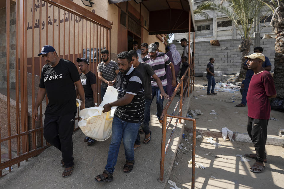 Mourners carry the covered bodies of Palestinians who were killed in an Israeli airstrike on a crowded tent camp housing Palestinians displaced by the war in the Muwasi, outside the hospital morgue in Deir al-Balah, Gaza Strip, Tuesday, Sept. 10, 2024. (AP Photo/Abdel Kareem Hana)