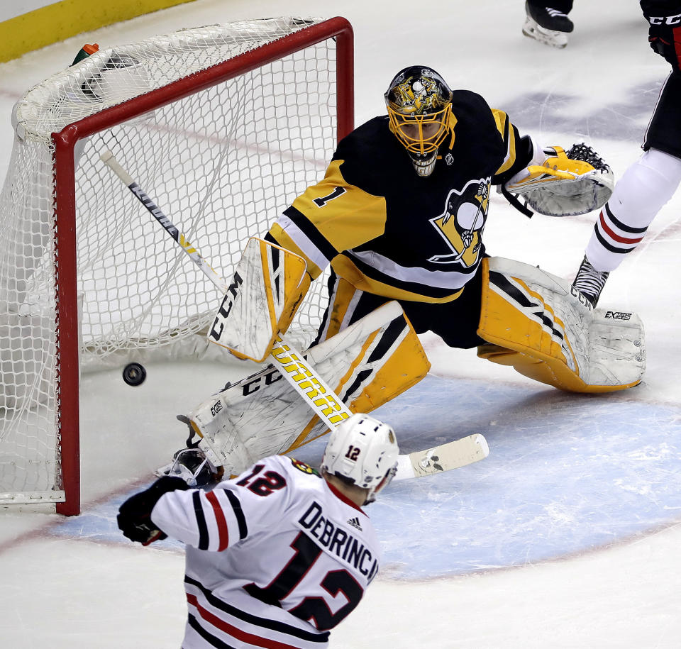 Chicago Blackhawks' Alex DeBrincat (12) puts the puck past Pittsburgh Penguins goaltender Casey DeSmith (1) for a power play goal in the first period of an NHL hockey game in Pittsburgh, Sunday, Jan. 6, 2019. (AP Photo/Gene J. Puskar)
