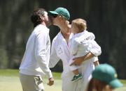 U.S. golfer Bubba Watson (L) kisses his wife Angie (C), who is holding their son Caleb, on the ninth green during the Par 3 Contest ahead of the 2014 Masters golf tournament at the Augusta National Golf Club in Augusta, Georgia April 9, 2014. REUTERS/Jim Young (UNITED STATES - Tags: SPORT GOLF)