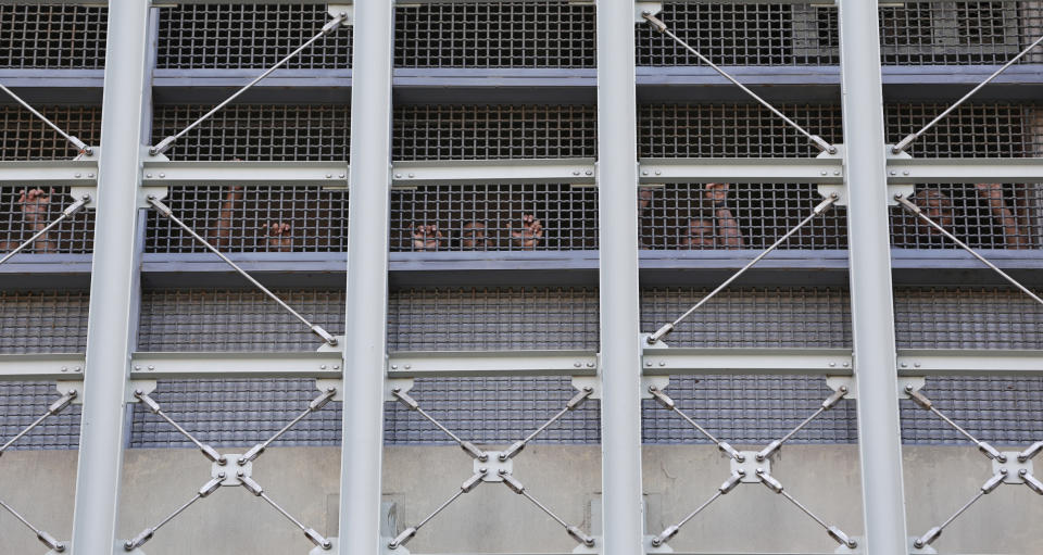 FILE - In this Sunday, Feb. 3, 2019, file photo, prisoners at the Metropolitan Detention Center, a federal facility in the Brooklyn borough of New York, respond to family members and people protesting the prison conditions. Prison employees and inmates say chilly temperatures inside a New York City federal lockup came weeks before a fire left some inmates without heat, light, hot water, and attorney and family visits for a week. The extent of the damage from the Jan. 27 fire was described in detail Tuesday at hearings in Manhattan and Brooklyn courts. (AP Photo/Kathy Willens, File)