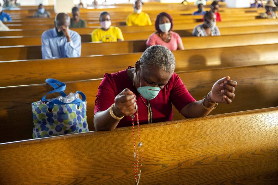 FILE - In this July 12, 2020 file photo, a woman prays during a Mass marking the reopening of places of worship at the Cathedral in Port-au-Prince, Haiti. Churches reopened after having been closed for months due to social distancing rules to curb the spread of the new coronavirus. (AP Photo/Dieu Nalio Chery, File)