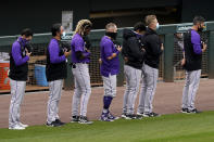 The Colorado Rockies observe a moment of silence in honor of those killed in the Boulder, Colo. supermarket shootings prior to a spring training baseball game against the Oakland Athletics, Tuesday, March 23, 2021, in Mesa, Ariz. (AP Photo/Matt York)