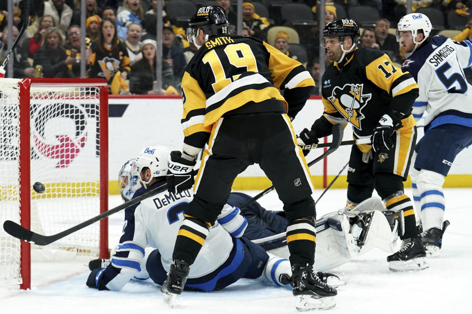 Pittsburgh Penguins' Bryan Rust (17), right, scores a goal on Winnipeg Jets goaltender Connor Hellebuyck (37) during the second period of an NHL hockey game, Tuesday, Feb. 6, 2024, in Pittsburgh. (AP Photo/Matt Freed)