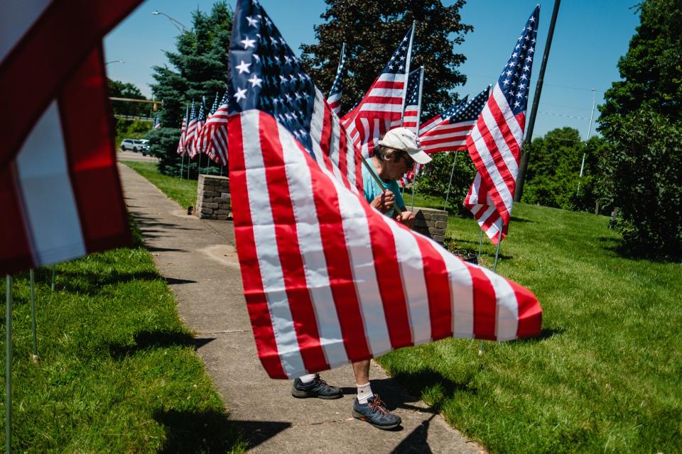 Tom Police of the New Philadelphia Rotary Club installs one of 50 flags as part of the Salute Freedom project at Commercial Avenue SE and South Broadway Street in New Philadelphia.