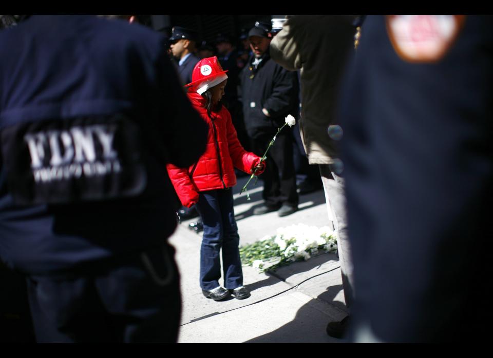 NEW YORK - MARCH 25:  A child places a flower at the site of theTriangle Shirtwaist Factory fire March 25, 2011 in New York City. The ceremony marked the 100 year anniversary of the fire which killed 146 immigrant workers, most of them young women. Workers were locked into the factory during their shifts, preventing escape. New Yorkers watched in horror from below as workers leapt to their deaths from the windows above. Public outcry over the tragedy led to nationwide debate on workers rights and safety regulations and helped pave the way for strong workers unions. (Photo by Eric Thayer/Getty Images)