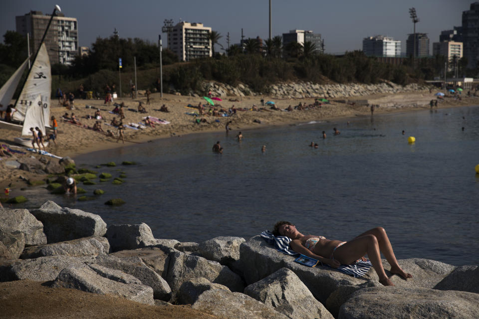 A woman rests next to the beach during a hot summer day in Barcelona, Spain, Friday, Aug. 3, 2018. Hot air from Africa is bringing a heat wave to Europe, prompting health warnings about Sahara Desert dust and exceptionally high temperatures that could peak at 47 degrees Celsius (117 Fahrenheit) in Spain and Portugal. (AP Photo/Emilio Morenatti)