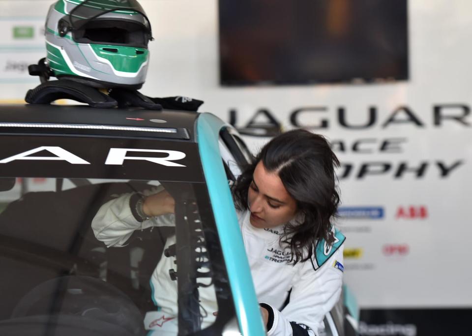 A woman climbs into her race car.