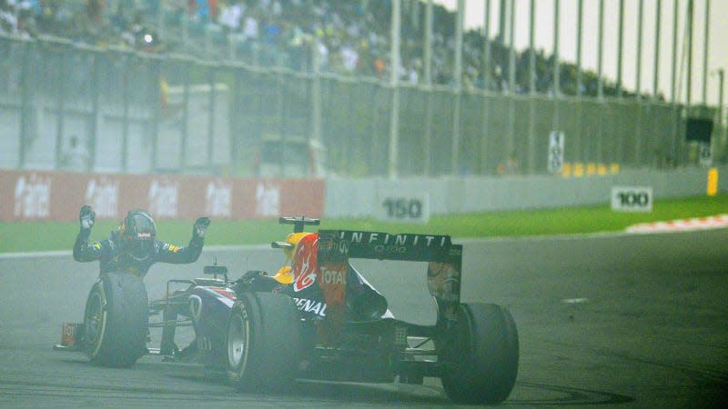 A photo of Sebastian Vettel bowing in front of his Red Bull Formula 1 car. 
