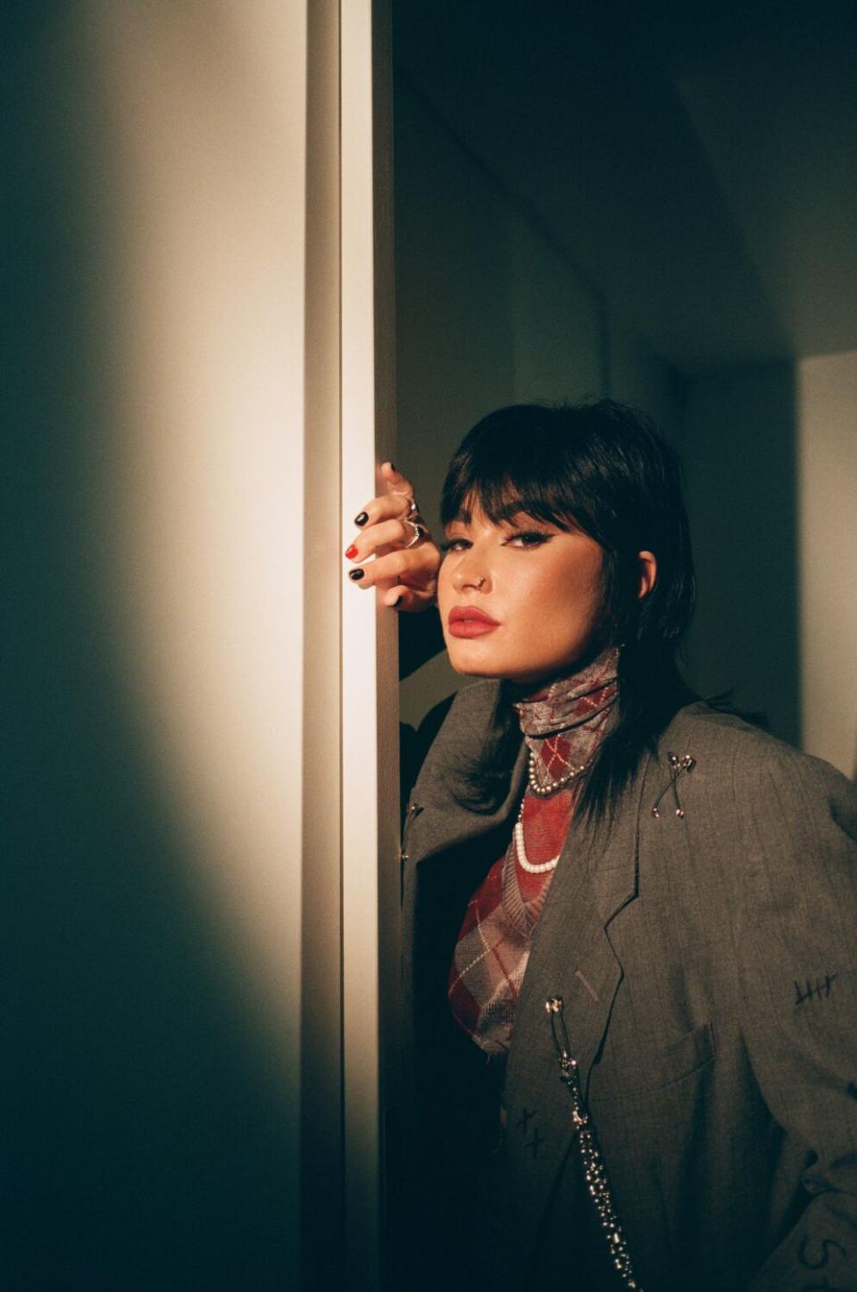 A young woman peering around a doorway.