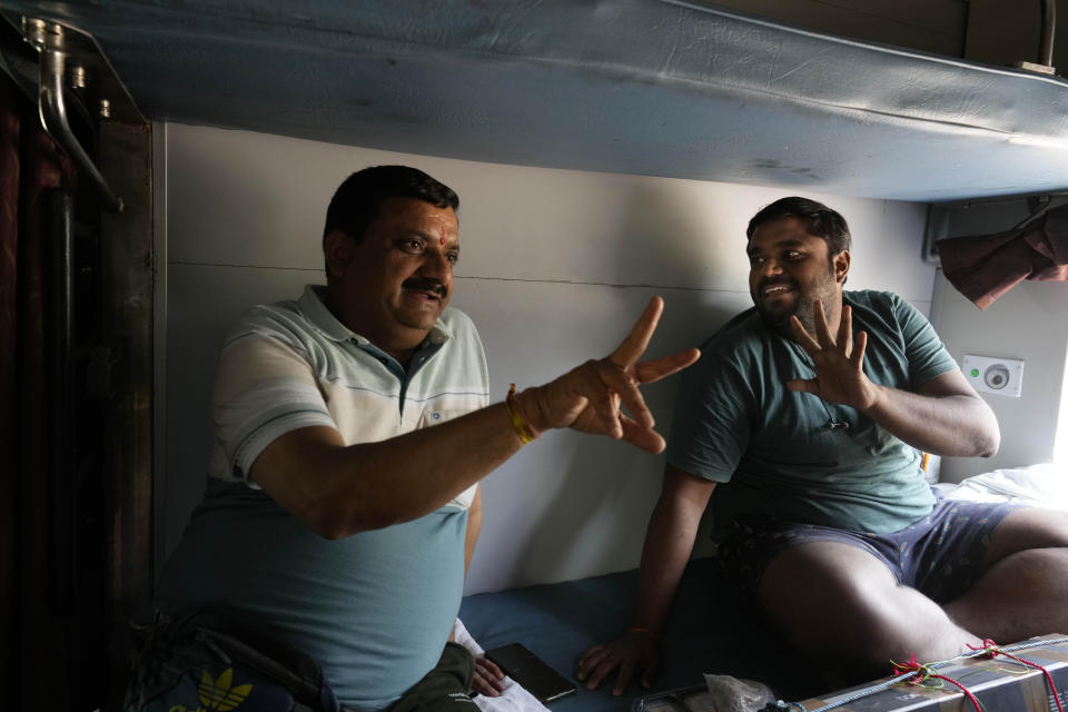 Mahadev Prasad, left, and Vinoth Kumar talk as they travel in air-conditioned sleeper compartment of the Thirukkural Express, India, Saturday, April 20, 2024. (AP Photo/Manish Swarup)