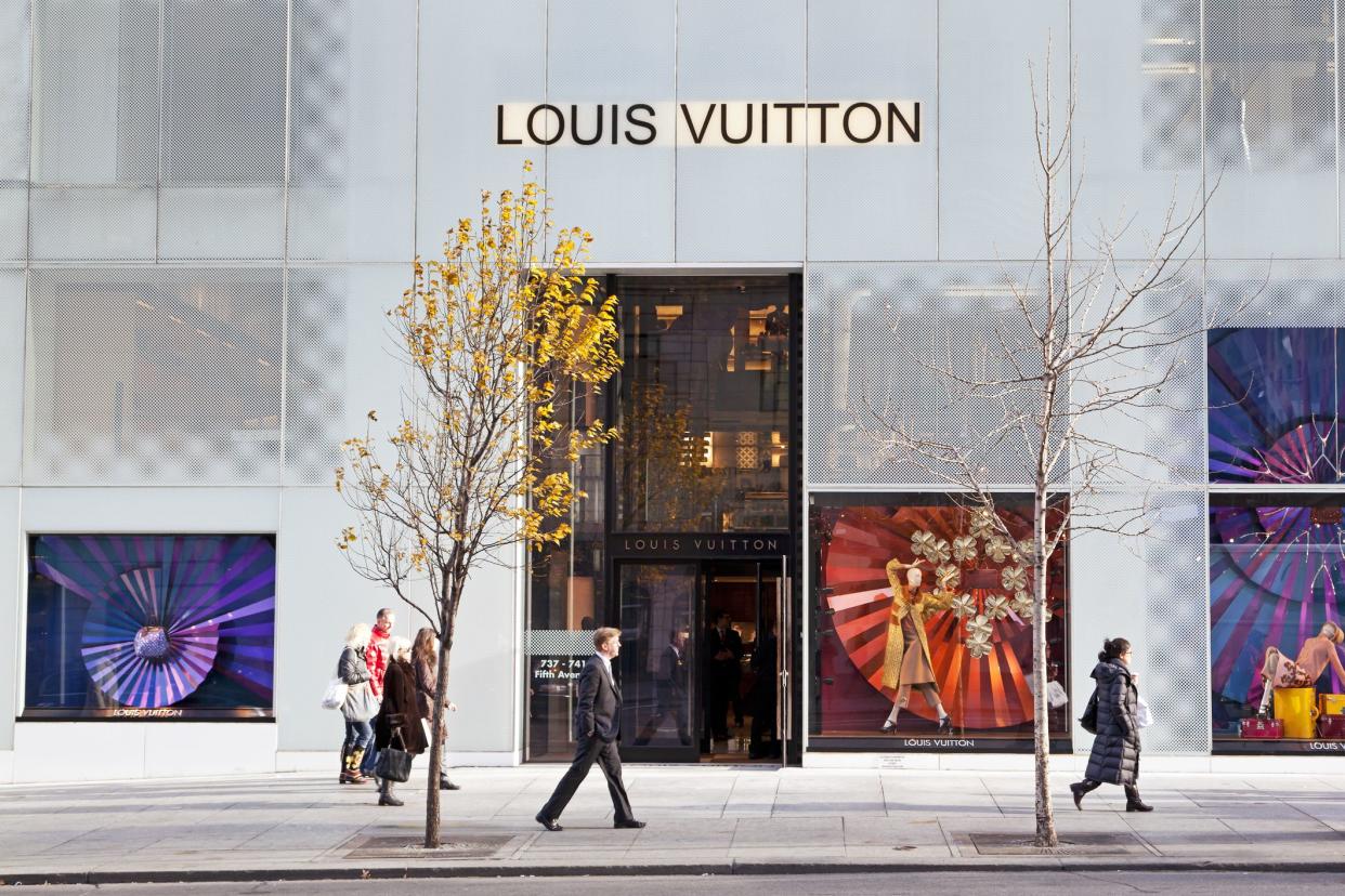 People walking on the sidewalk in front of the Louis Vuitton store at Fifth avenue."