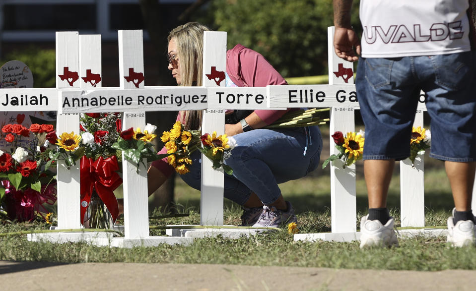 A mourner places flowers by each of the wooden crosses at a memorial site for the victims of the Robb Elementary School shooting, Thursday, May 26, 2022, in Uvalde, Texas. (Kin Man Hui/The San Antonio Express-News via AP)