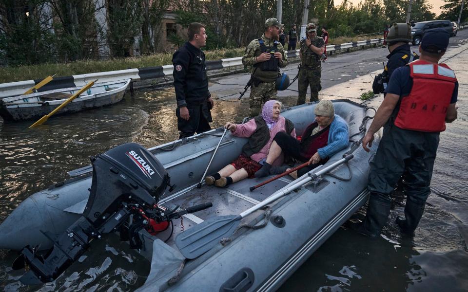 Rescue workers attempt to tow boats carrying residents being evacuated from a flooded neighborhood in Kherson - Libkos