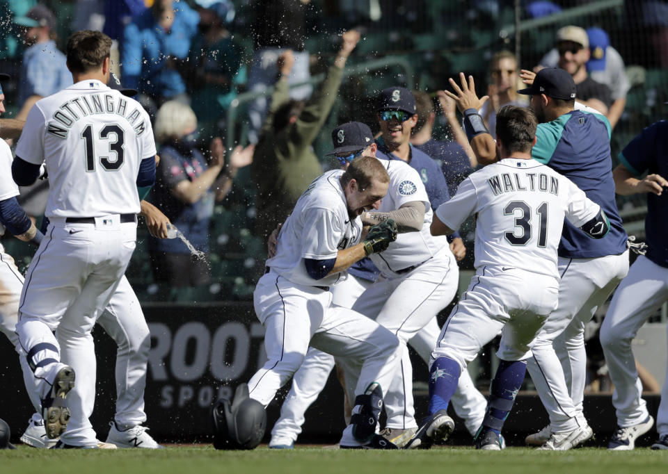 Seattle Mariners players surround Tom Murphy, center, after he hit a sacrifice fly, scoring the winning run, in the 10th inning against the Oakland Athletics during a baseball game, Monday, May 31, 2021, in Seattle. (AP Photo/John Froschauer)