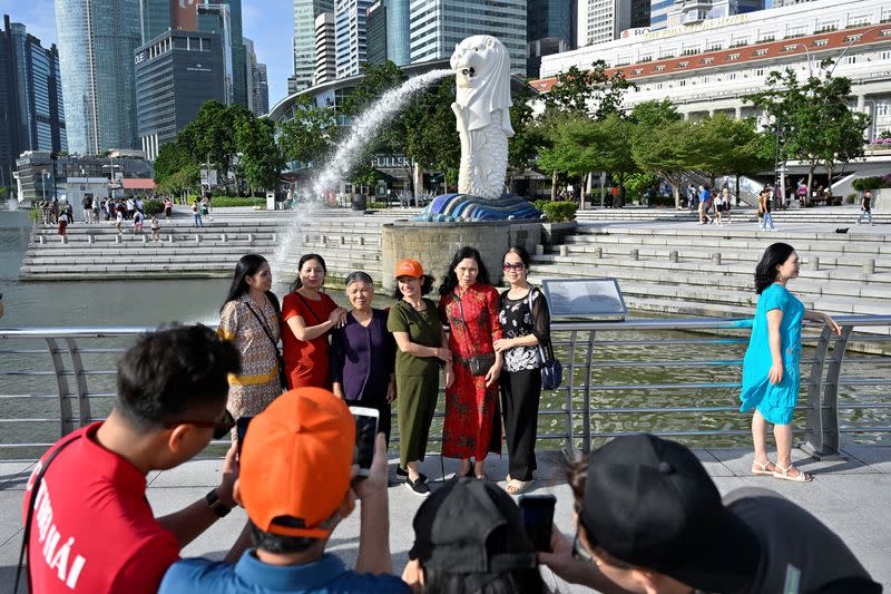 FILE PHOTO: Tourists pose for photographs at Merlion Park in Singapore