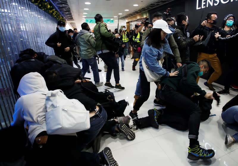 Plain-cloth police officers detain anti-government protesters inside the Sheung Shui shopping mall in Hong Kong
