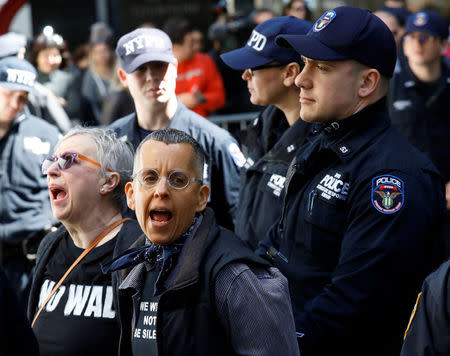 A New York City Police officer (NYPD) escorts protestors after making arrests for demonstrating in Trump Tower in New York, U.S., April 13, 2017. REUTERS/Brendan McDermid