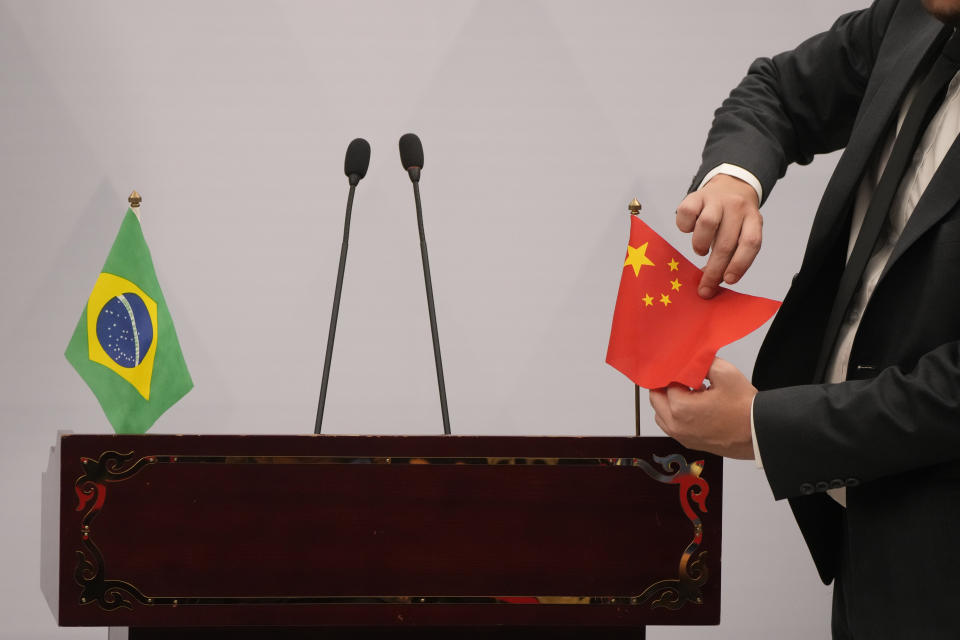 A man adjusts the Chinese flag during a press conference at the Brazilian embassy to Beijing in Beijing, Friday, April 14, 2023. Chinese leader Xi Jinping has met with visiting Brazilian President Luiz Inácio Lula da Silva as part of a push to boost ties between two of the world's largest developing nations. (AP Photo/Mark Schifelbein)
