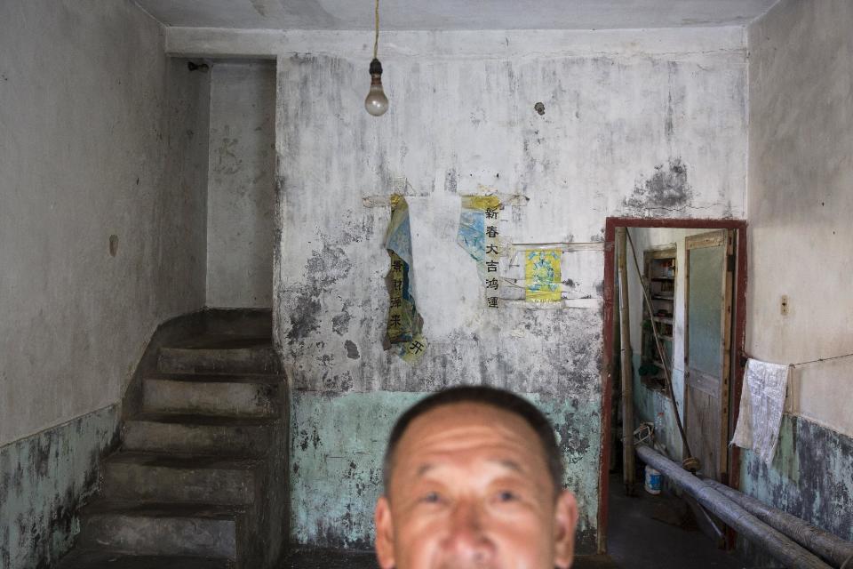 Sun Ayue, one of a few remaining residents, stands in his home in the abandoned fishing village of Houtouwan on the island of Shengshan July 26, 2015. (REUTERS/Damir Sagolj)