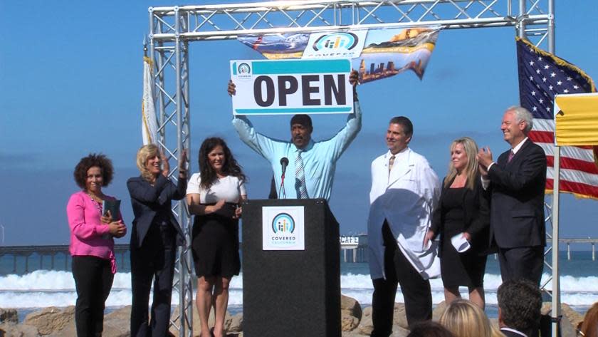 In 2013, Covered California board member Robert Ross, center, declares the start of the exchange's first open-enrollment period.