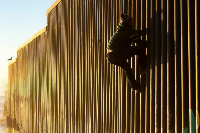 A Honduran migrant climbs the US-Mexico border fence on December 8, 2018