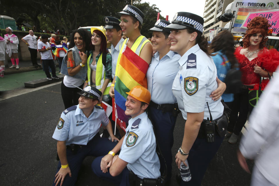 FILE - New South Wales state police pose with participants in the annual gay and lesbian Mardi Gras parade in Sydney, March 1, 2014. Organizers of the Sydney Gay and Lesbian Mardi Gras have asked police not to march at their annual parade at the weekend due to an alleged murder of a couple by a police officer, prompting the police commissioner on Tuesday, Feb, 27, 2024, to urge the ban be reversed. (AP Photo/Rick Rycroft, File)