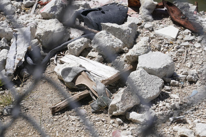 A shoe is seen amid debris at the edge of what remains of the Champlain Towers South condominium building Thursday, May 12, 2022, in Surfside, Fla. A large banner was installed around the site with the names of the 98 killed when the building suddenly collapsed nearly a year ago. (AP Photo/Marta Lavandier)