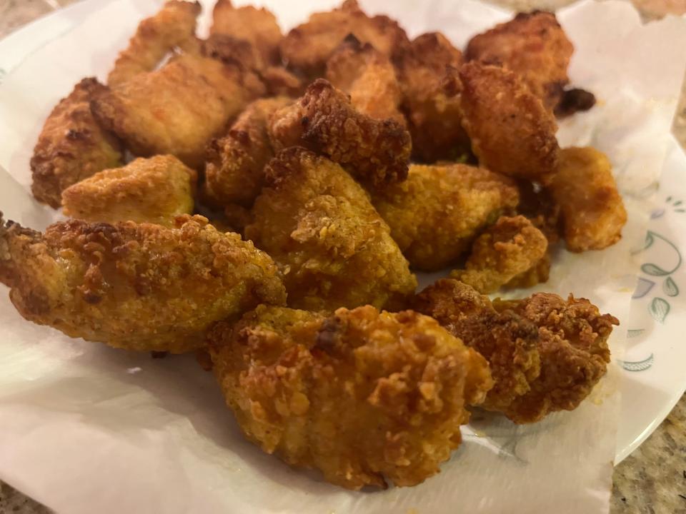 Golden-brown crispy chunks of chicken breast with breading on them
